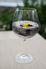 transparent cocktail in a glass decorated with flowers on a table on the terrace
