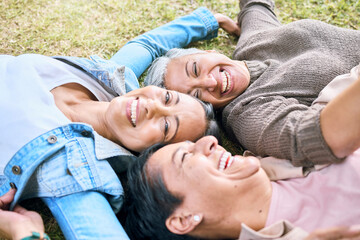 Elderly, happy or friends on grass in a park talking or speaking of funny gossip relaxing holiday...