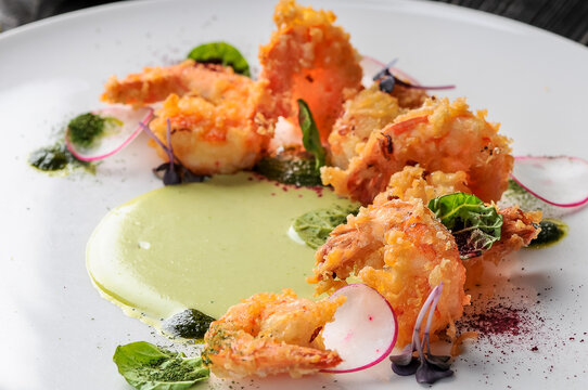 fried shrimp in batter in a plate with greens and radish macro
