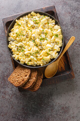 German egg salad with apples and pickles dressed with mayonnaise close-up in a bowl on the table. Vertical top view from above