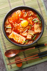 Sundubu Jjigae Spicy Kimchi Soft Tofu Stew closeup on the bowl on the table. Vertical top view from above