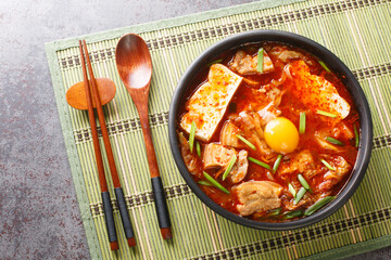 Sundubu Jjigae or soft tofu stew, is a traditional Korean dish made with silky soft uncurdled tofu coated in a spicy and flavorful broth closeup on the bowl. Horizontal top view from above