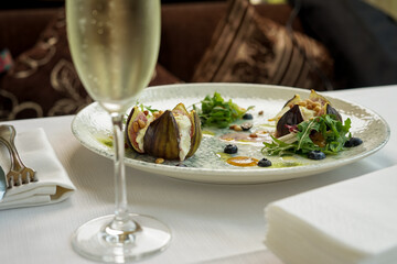baked figs with cheese and pine nuts in a plate with salad on the table
