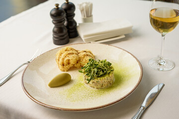 Olivier salad decorated with microgreens in a bowl of porridge on the table with a glass of white wine
