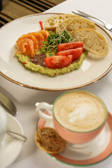 guacamole with shrimp and tomatoes in a plate with bruschetta on the table with coffee
