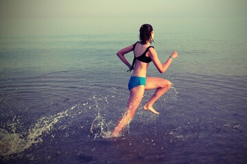 girl runs on the sea water during training with antique effect tones