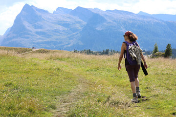 Fototapeta na wymiar young woman hiker walks in the high mountain trail in the Italian Alps on the Dolomites mountain range