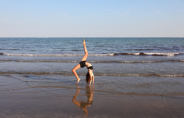 young slim athletic girl performs gymnastic exercises in summer