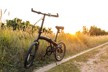 Obraz premium Bicycle stands on a country road at sunset, a break in a bike ride