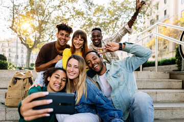 Multiracial young happy group of student friends taking selfie portrait together using mobile phone...