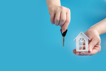 mortgage, real estate loan, buying and renting property, house and key in hand on a blue background, copy space