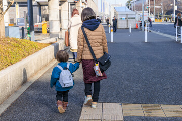 母親に手を引かれる青いリュックを背負った子