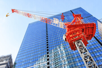 新しい高層ビルを建設するための赤白のクレーン © captainT