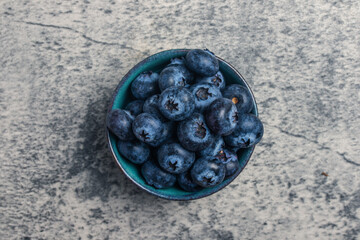 Raw Organic Blueberries in a Bowl on a gray background,