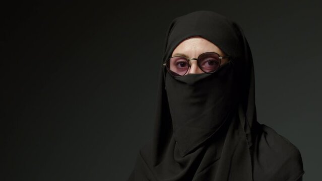 Close-up portrait of a Muslim woman with beautiful eyes in a hijab on a dark background. A girl in a black headscarf is looking at the camera. Arab women life concept