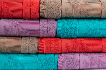 multicolored terry towels, rolled up and stacked on the table