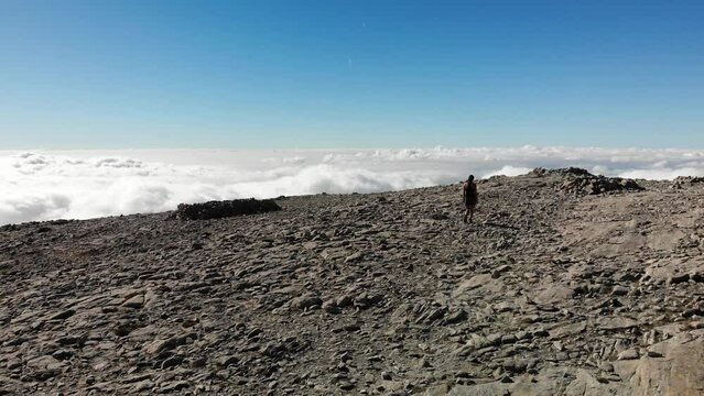4K drone footage over woman walking on a rocky peak with sea of clouds on the back at La Maroma summit, Malaga, Spain.
Mid angle, traveling movement.
