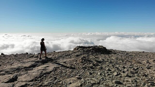 4K drone footage over woman walking on a rocky peak with sea of clouds on the back at La Maroma summit, Malaga, Spain.
Mid angle, traveling movement.