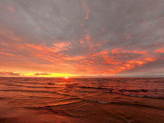 Beautiful sunset on the sea coast, the sun on a background of sky and clouds