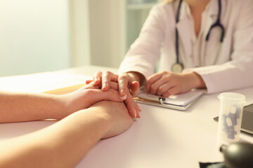 Doctor with his hand calming patient in clinic closeup
