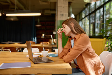 Tired young business woman working at coworking space