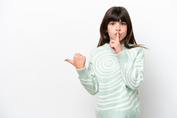 Little caucasian girl isolated on white background pointing to the side and doing silence gesture