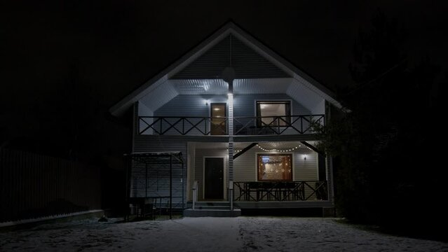 House exterior in winter time, night, Christmas holiday. Home outdoor, outside, decorated with lights in darkness