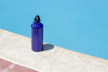 Blue lightweight aluminum reusable bottle on the poolside