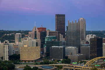 Fototapeta premium Cityscape of Pittsburgh and Evening Light. Fort Pitt Bridge. Blurry Ferry Cruise in Background Because of Long Exposure. Selective focus.