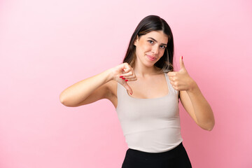 Young Italian woman isolated on pink background making good-bad sign. Undecided between yes or not