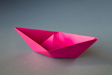 Pink paper boat origami isolated on a grey background