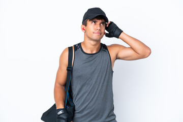 Young sport caucasian man with sport bag isolated on white background having doubts and with...