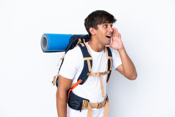 Young mountaineer woman with a big backpack over isolated white background shouting with mouth wide open to the lateral