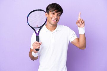 Handsome young tennis player man isolated on ocher background pointing up a great idea