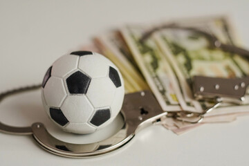Soccer ball with money and handcuffs. Corruption in football, gambling and bribery in sport concept.