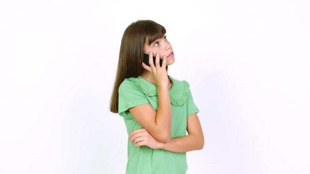 Little girl keeping a conversation with the mobile phone over isolated background