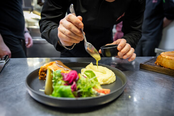 chef hand preparing Meat Pie with mashed potato and salad on restaurant kitchen