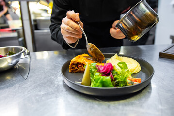 chef hand preparing Meat Pie with mashed potato and salad on restaurant kitchen