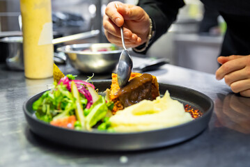 chef hand preparing Meat Pie with mashed potato and salad on restaurant kitchen