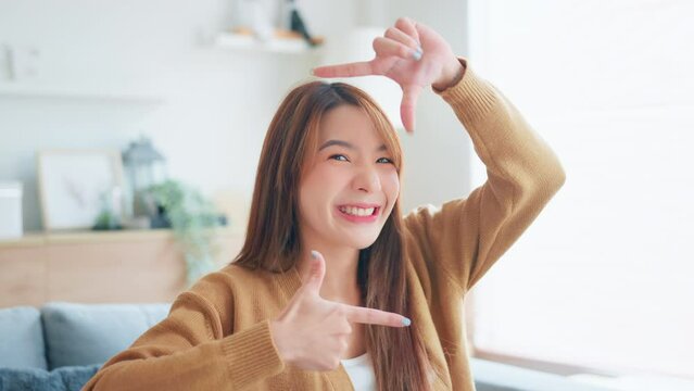 Happy young asian woman hands making frame shape and looking in camera, Lovely female having fun posing in creative way.