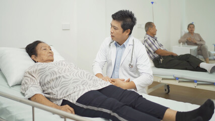 Fototapeta premium An Asian doctor with a group of old elderly patient or pensioner in nursing home in hospital. Senior people lifestyle activity recreation. Health care physical therapy.