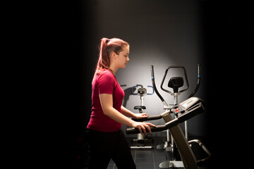 Fototapeta na wymiar Young woman at the gym walks on a treadmill