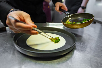 chef hand cooking broccoli with cheese sauce on restaurant kitchen