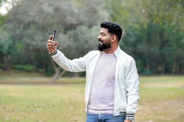 Young indian man using smartphone at park