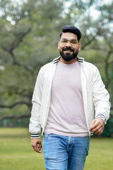Young and confident indian man giving expression at park.