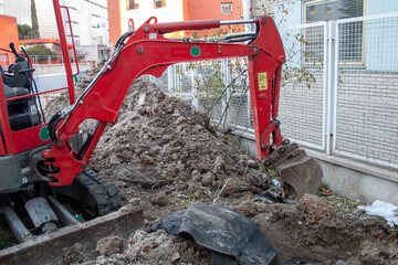 mini Backhoe stopped, inside a fenced enclosure, on the construction site ready to start and work...