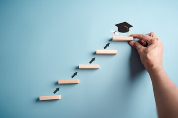 Steps of education leading to success goal. Taking strategic steps towards graduation. Career path and first for business, Graduation achievement goals concept. Graduation cap on wooden block. - obrazy, fototapety, plakaty