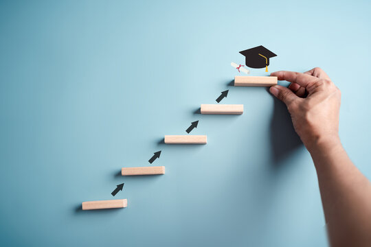 Steps of education leading to success goal. Taking strategic steps towards graduation. Career path and first for business, Graduation achievement goals concept. Graduation cap on wooden block.