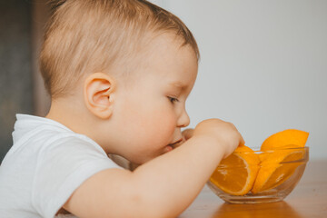 a child eats an orange cut into slices close-up