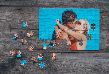 Puzzle with a photo of a kissing couple on a wooden background. Gift idea for Valentine's Day.